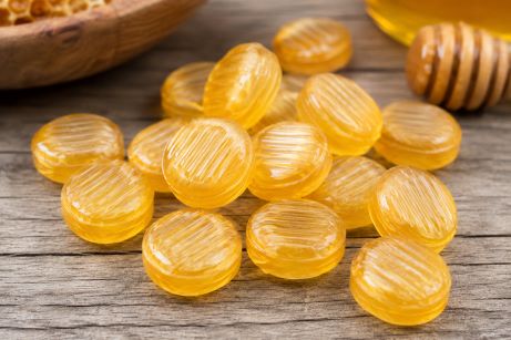 Goldgelbe Honigbonbons mit echtem Honig auf einem Holztisch.